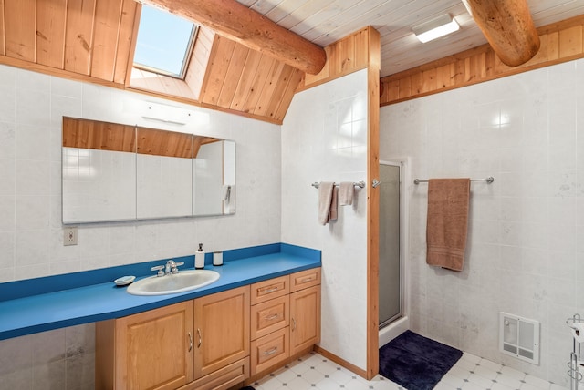 bathroom with tile patterned floors, vaulted ceiling with skylight, tile walls, and visible vents