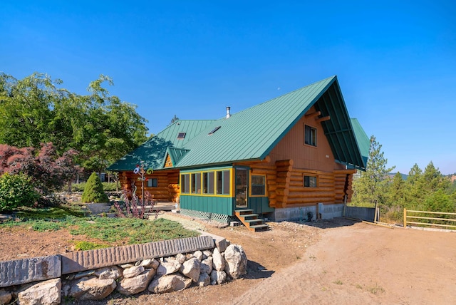 back of property featuring log siding, entry steps, metal roof, and fence