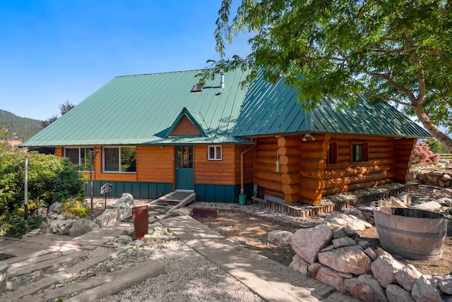 log-style house with log siding, entry steps, and metal roof