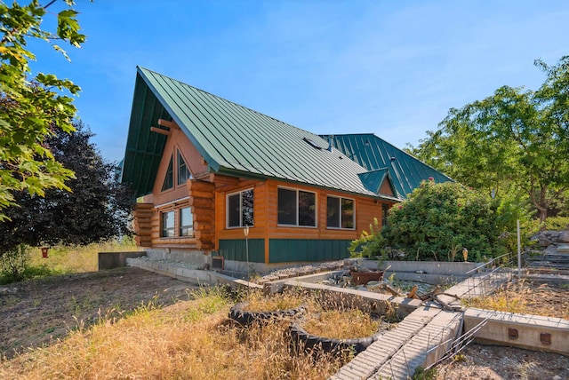 view of property exterior with a standing seam roof, log exterior, and metal roof