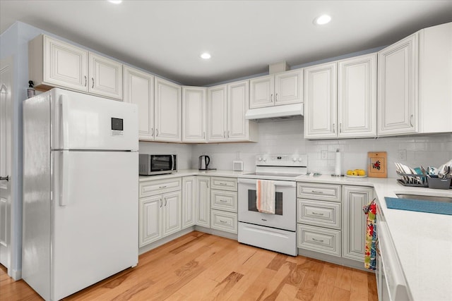 kitchen featuring under cabinet range hood, backsplash, white appliances, light wood-style floors, and light countertops