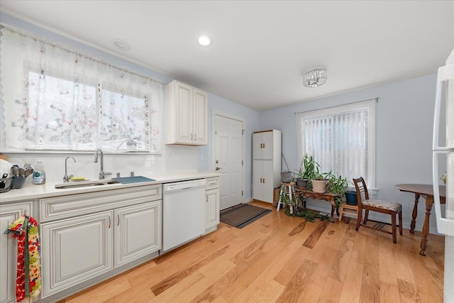 kitchen featuring light wood-style flooring, a sink, light countertops, dishwasher, and backsplash