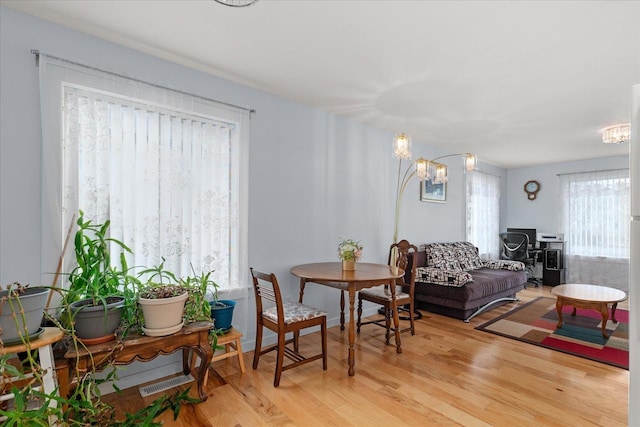 living area with light wood finished floors, baseboards, and an inviting chandelier