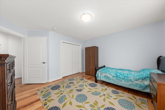 bedroom with baseboards, light wood-type flooring, and a closet