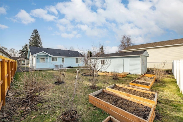 back of house featuring an outdoor structure, a garden, and a fenced backyard