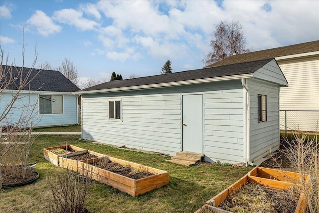 view of outdoor structure featuring a garden, entry steps, an outdoor structure, and fence