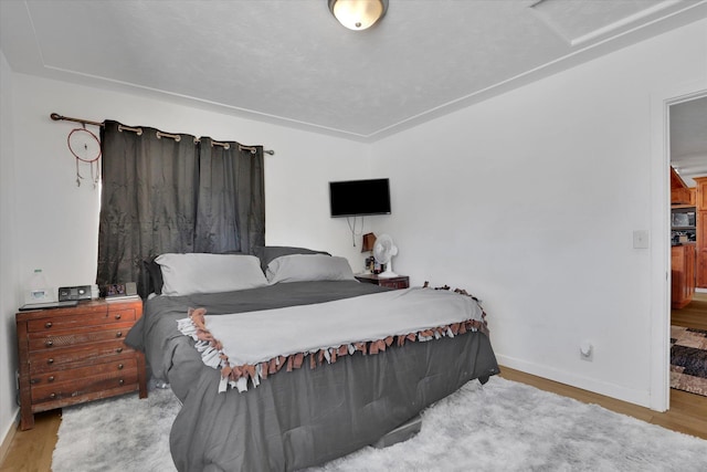 bedroom with attic access, wood finished floors, and baseboards