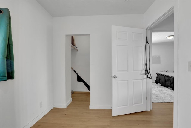 hallway with light wood-type flooring and baseboards