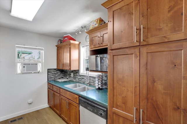 kitchen featuring visible vents, light wood-style flooring, a sink, stainless steel dishwasher, and backsplash