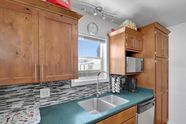 kitchen featuring dark countertops, backsplash, dishwasher, brown cabinets, and a sink