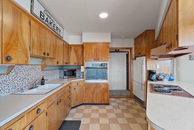 kitchen with light floors, a sink, wall oven, stainless steel microwave, and white refrigerator