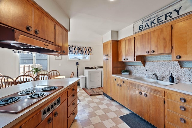 kitchen featuring a sink, washing machine and dryer, stainless steel electric stovetop, light countertops, and light floors