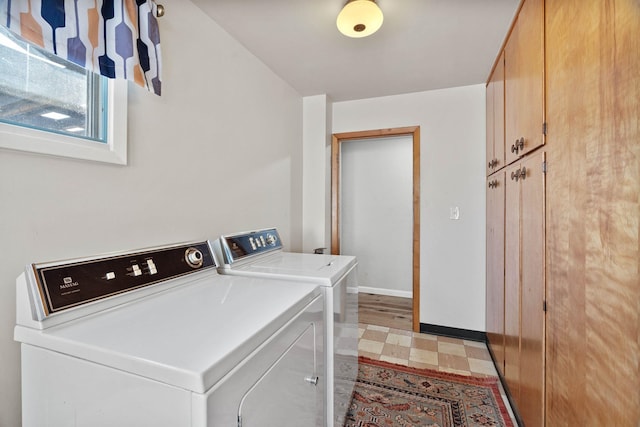 laundry room with cabinet space, baseboards, light floors, and washing machine and clothes dryer