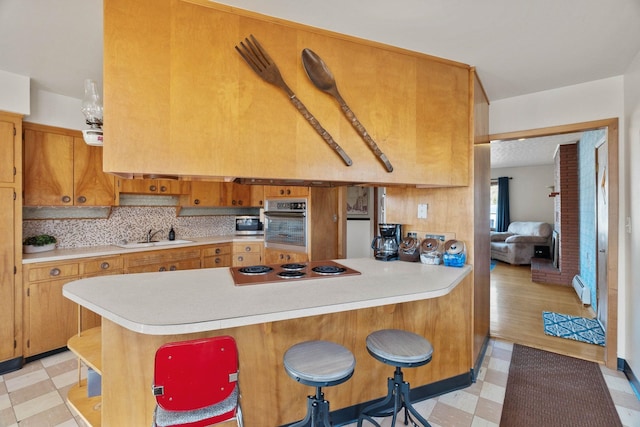 kitchen with light countertops, stovetop, light floors, and a baseboard radiator