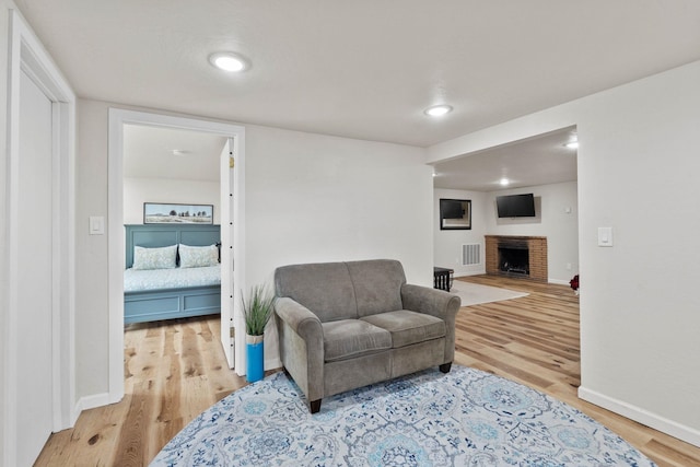 living area with visible vents, a fireplace, baseboards, and wood finished floors