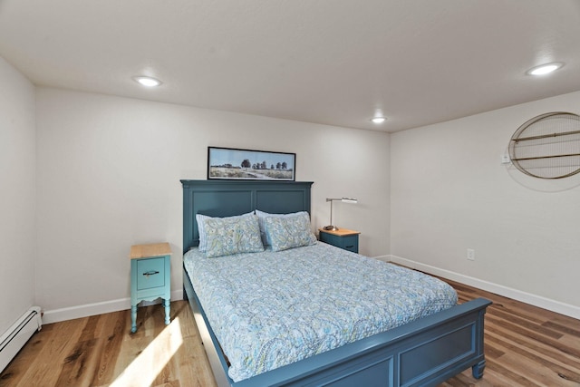 bedroom featuring a baseboard heating unit, recessed lighting, wood finished floors, and baseboards