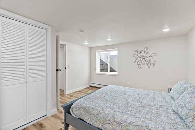 bedroom featuring light wood-style flooring, recessed lighting, a closet, baseboards, and baseboard heating