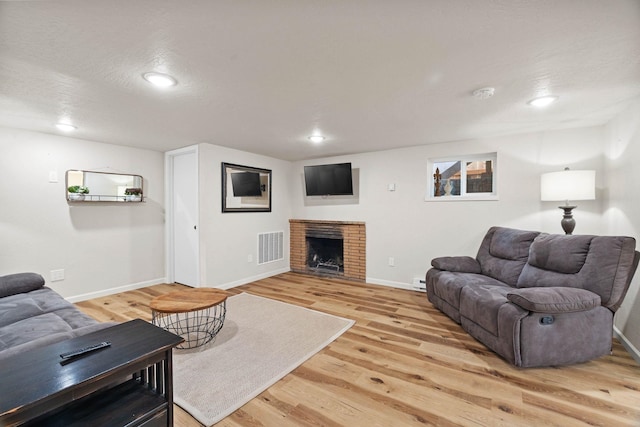 living room featuring visible vents, baseboards, a fireplace, recessed lighting, and light wood-type flooring