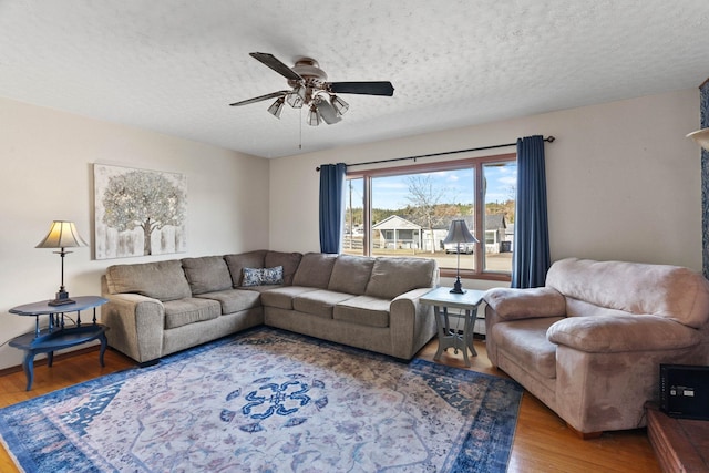 living area with a ceiling fan, wood finished floors, and a textured ceiling