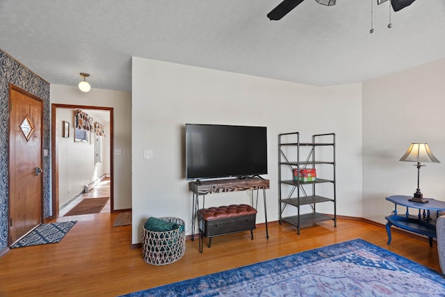 interior space featuring a textured ceiling, baseboards, ceiling fan, and wood finished floors