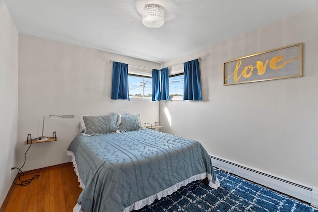 bedroom with a baseboard radiator, baseboards, and wood finished floors