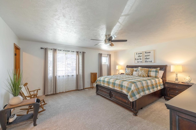 bedroom featuring a textured ceiling, light colored carpet, and ceiling fan