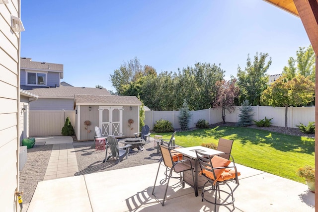 view of patio featuring an outbuilding, a fire pit, a fenced backyard, and a storage shed