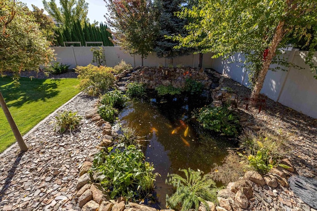 view of yard featuring a fenced backyard and a small pond