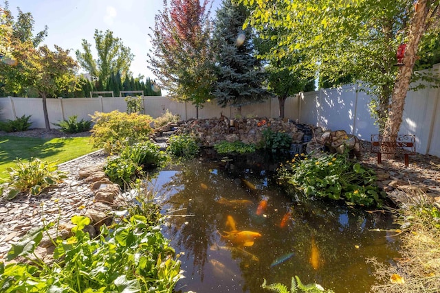 view of yard featuring a garden pond and a fenced backyard