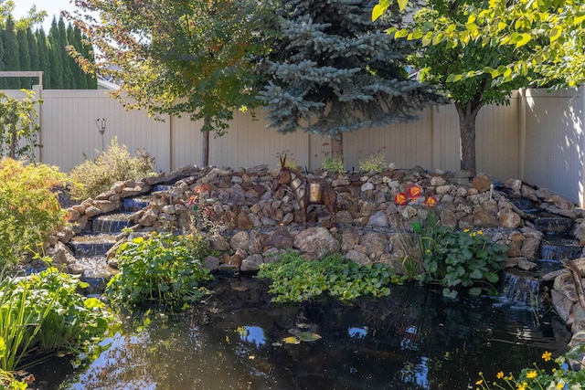 view of yard featuring fence and a small pond