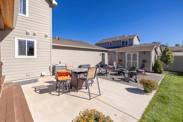 view of patio featuring an outbuilding, fence, a fire pit, a storage shed, and central AC unit