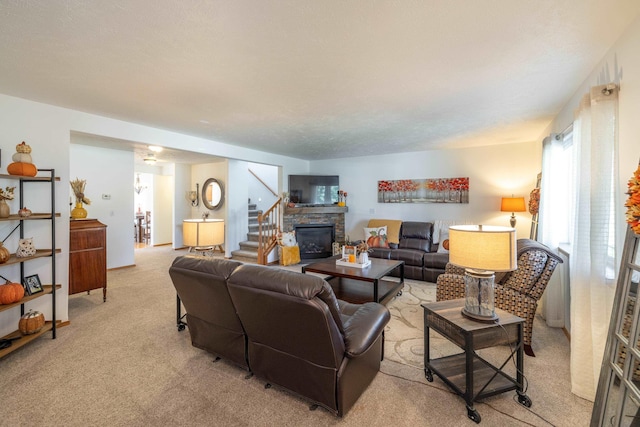 living room with light carpet, a stone fireplace, and stairway