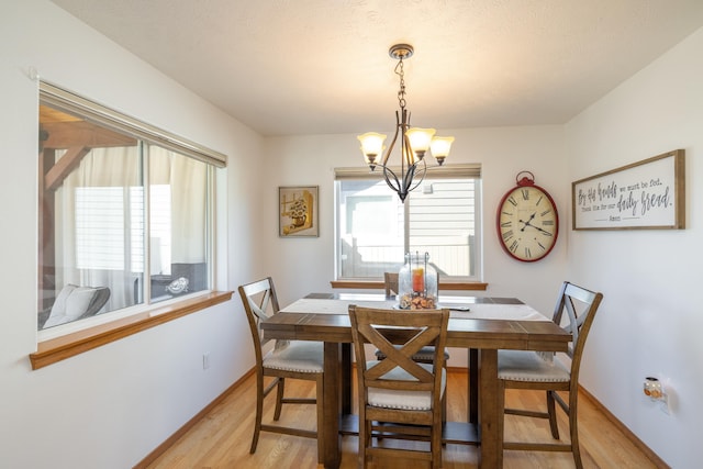 dining area featuring an inviting chandelier, light wood-style flooring, and baseboards