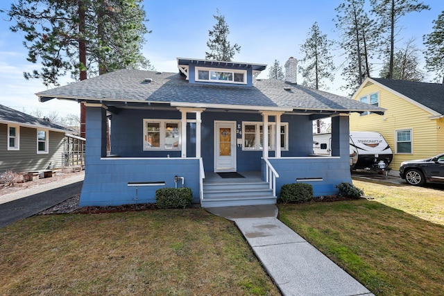 bungalow-style house featuring a chimney, a porch, a front yard, and a shingled roof