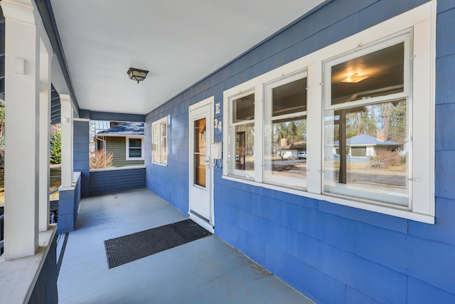 view of exterior entry featuring a porch and concrete block siding