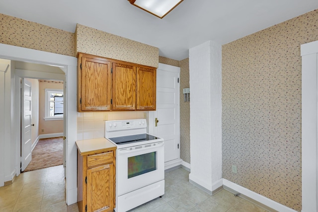 kitchen featuring white electric stove and wallpapered walls