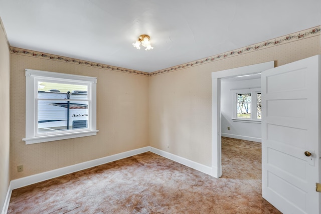 unfurnished room featuring wallpapered walls, baseboards, and light carpet