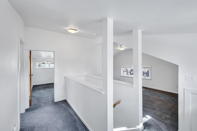 hall featuring an upstairs landing, vaulted ceiling, baseboards, and carpet floors