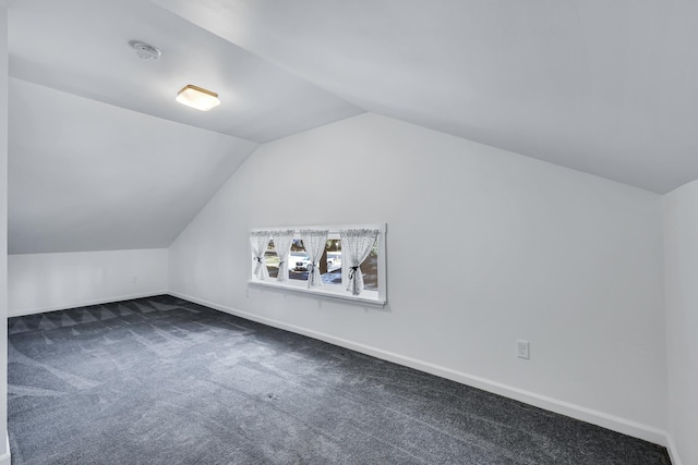 bonus room with dark carpet, baseboards, and vaulted ceiling