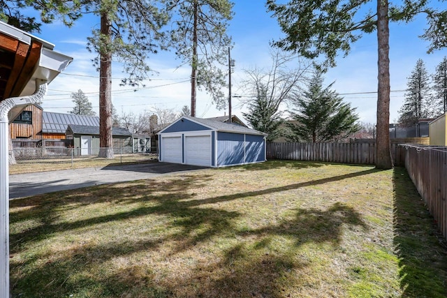 view of yard with a garage, fence private yard, and an outdoor structure