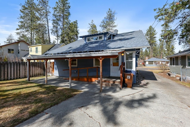 view of front of home with a front lawn, a porch, fence, roof with shingles, and an attached carport