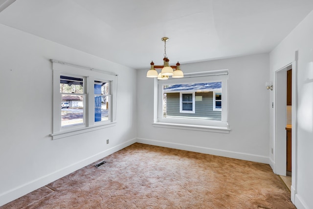 empty room featuring light colored carpet, baseboards, visible vents, and a chandelier