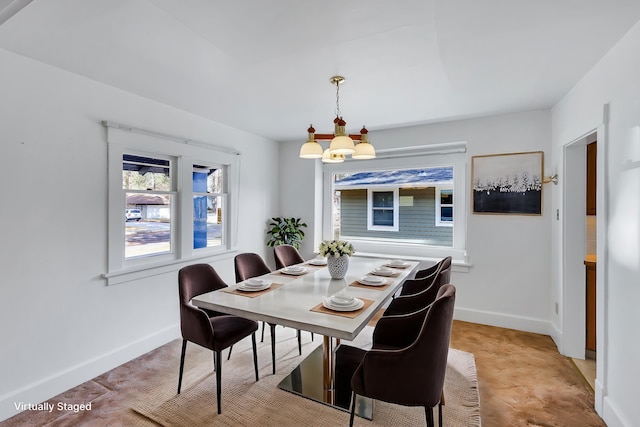 dining room featuring a notable chandelier and baseboards