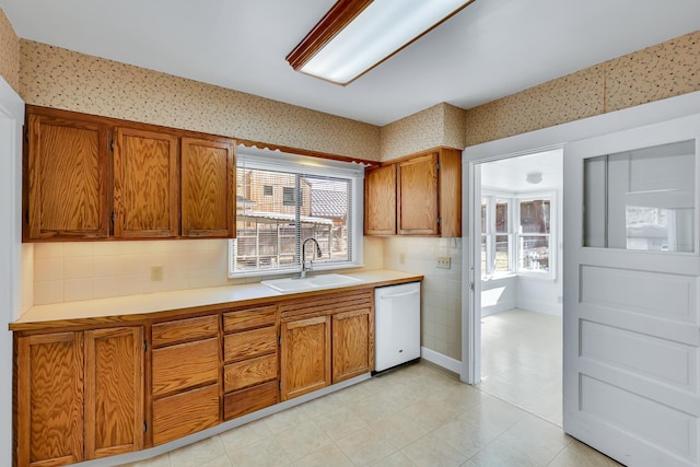 kitchen with brown cabinetry, dishwasher, and a sink