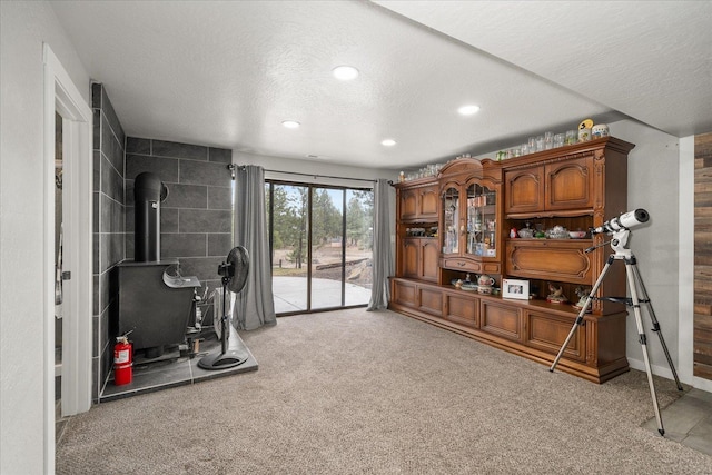 workout room with baseboards, a wood stove, recessed lighting, a textured ceiling, and light colored carpet