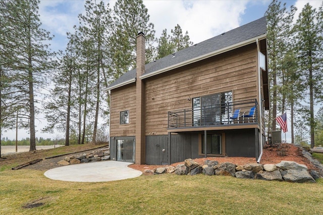 back of property featuring a lawn, a patio, cooling unit, an attached garage, and a chimney