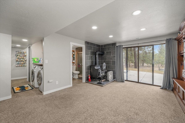 interior space with a wood stove, carpet, independent washer and dryer, and a textured ceiling