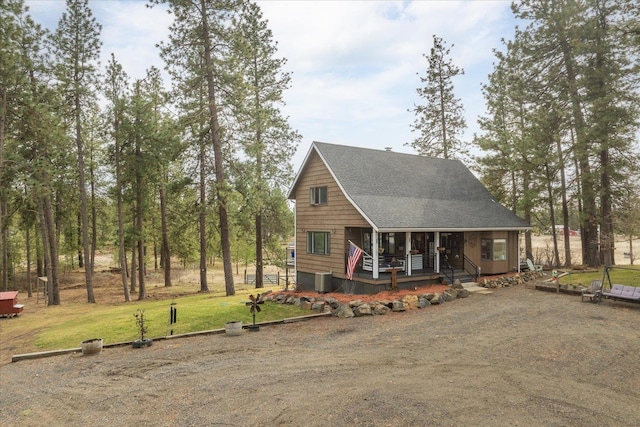 view of front of home with a porch, central AC unit, a front lawn, and roof with shingles