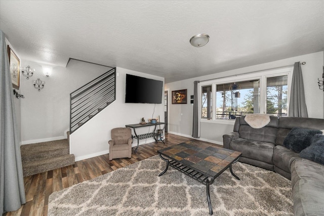 living area with stairway, wood finished floors, baseboards, and a textured ceiling