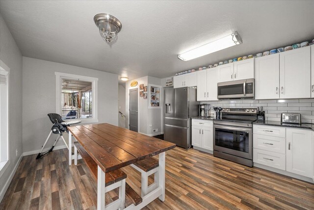 kitchen with dark countertops, backsplash, stainless steel appliances, and dark wood-type flooring